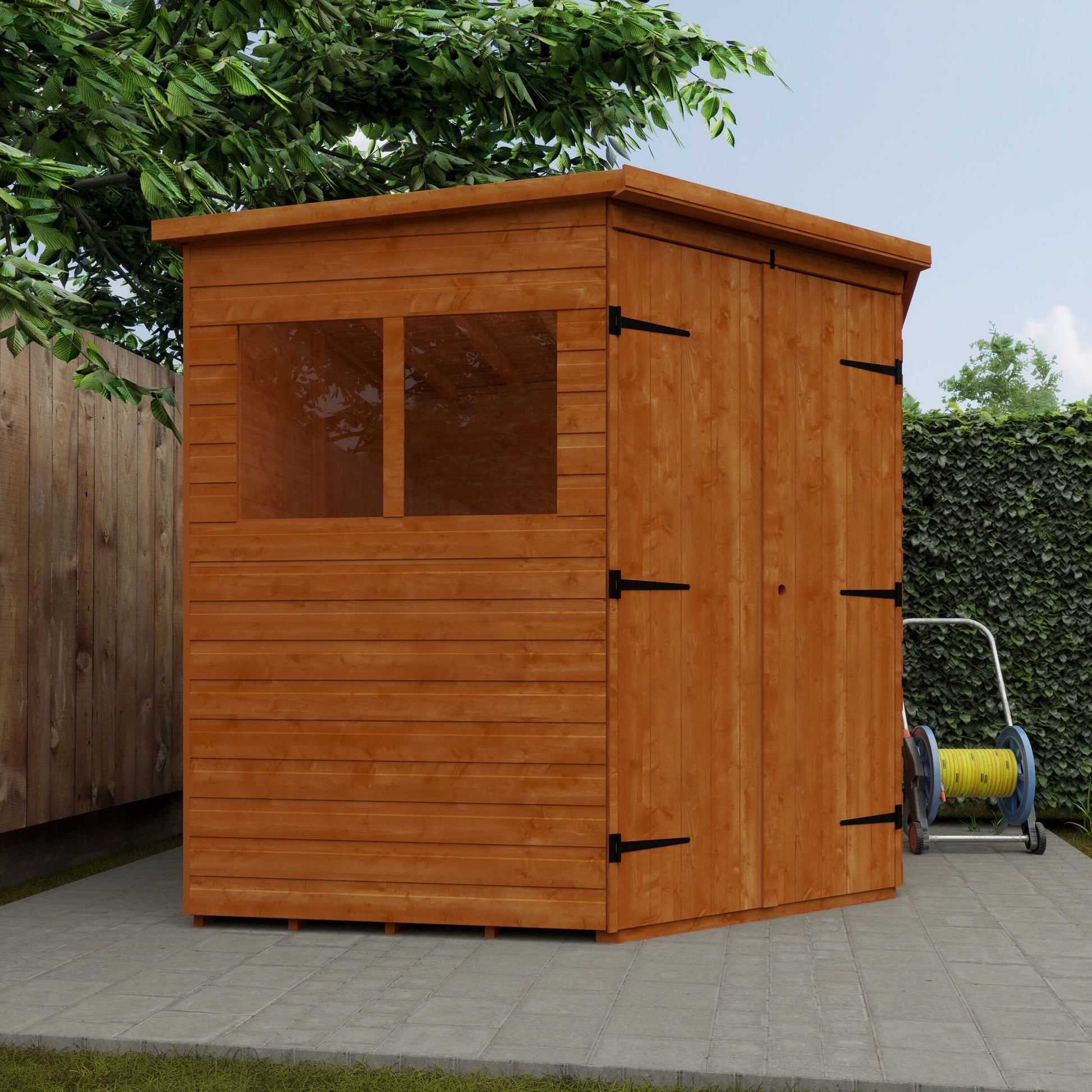 Wooden shed with a door and window on a paved area with greenery in the background